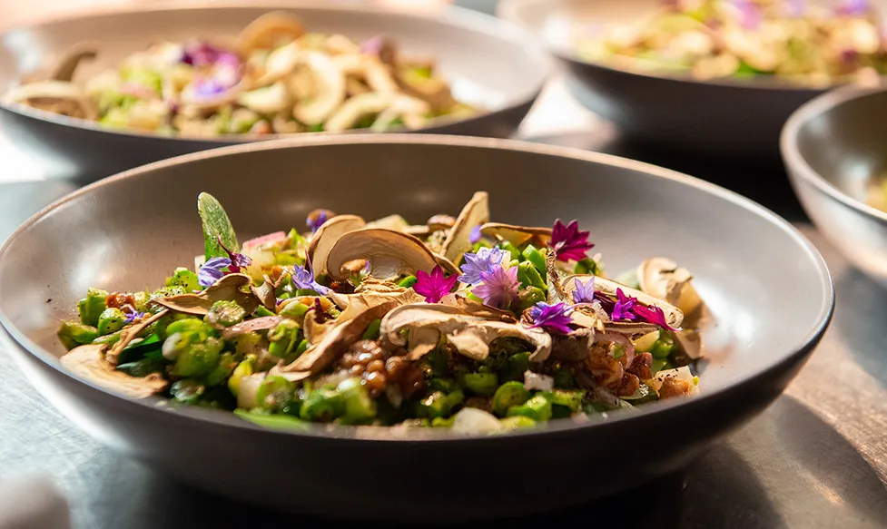 A beautiful plate of fresh mushrooms and greens adorned with edible flowers