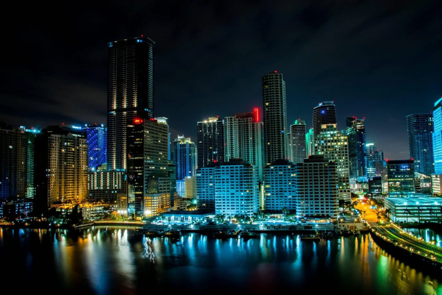 The skyscrapers of Downtown Miami are brilliantly lit up in shades of bright blue under the cover of the night sky
