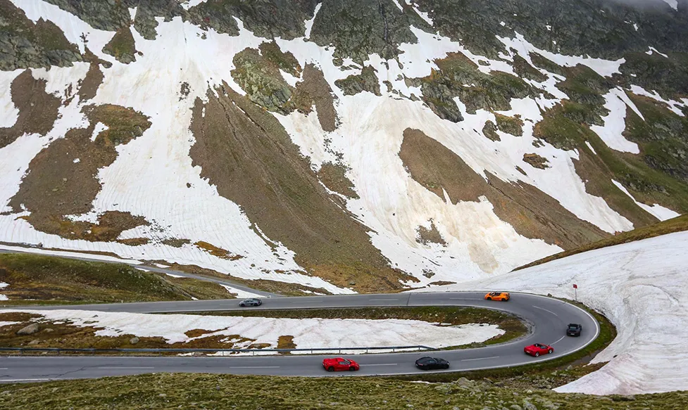 Supercars turning into a hairpin bend on the Grimsel Pass in Switzerland