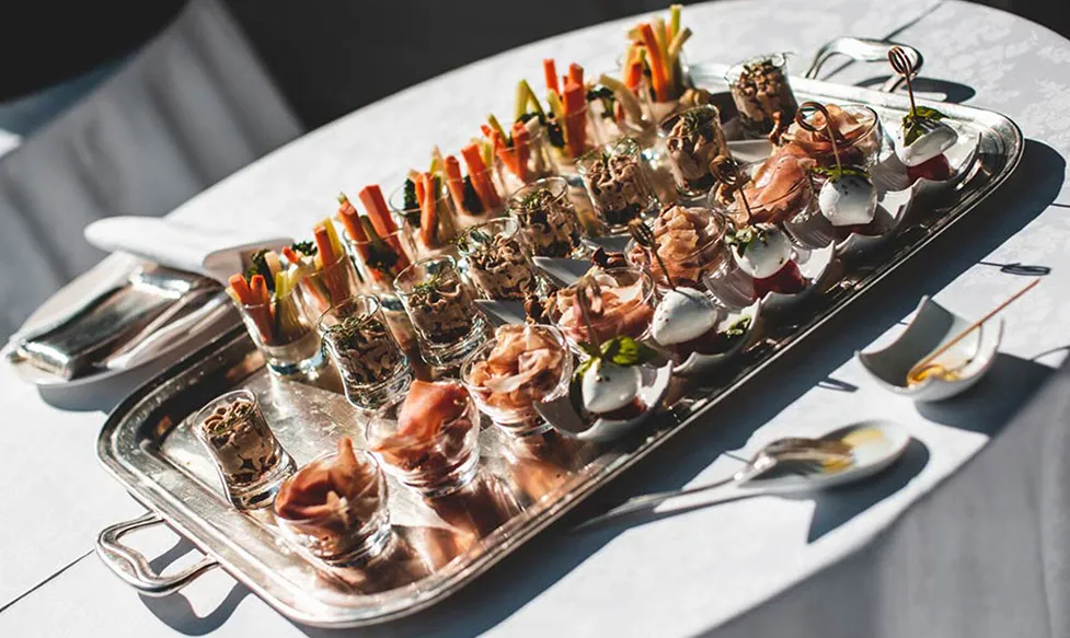 A silver platter holds delicate canapés in decorative glasses ready for serving to Ultimate Driving Tours’; guests in Italy