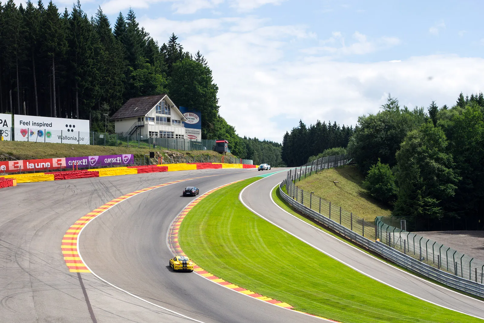 Yellow and white Porsches at Eau Rouge corner at Spa Francorchamps